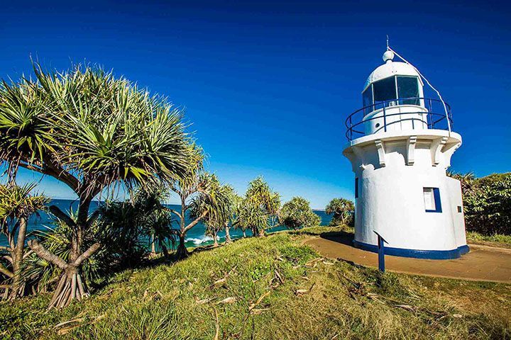 A White Lighthouse Is Sitting On Top Of A Grassy Hill Next To The Ocean — Mr Steam Clean Tweed Coast In Tweed Heads, NSW