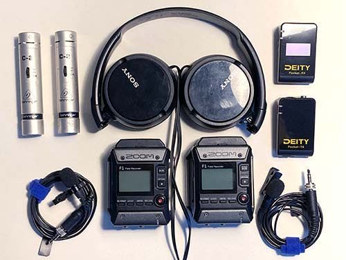 Two wireless microphones with headphones, bodypacks, batteries, and cables arranged on a white background