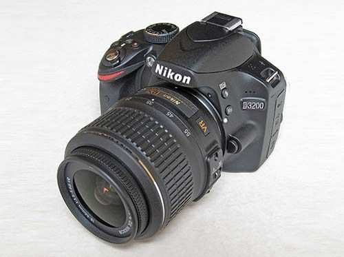 Nikon DSLR camera with attached zoom lens on a white background