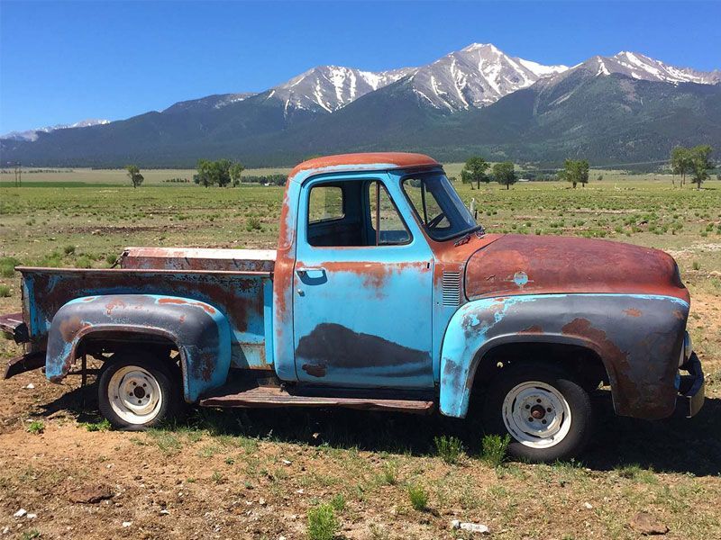 Rusty blue vintage pickup truck in a field with mountains in the background, Buena Vista, Colorado