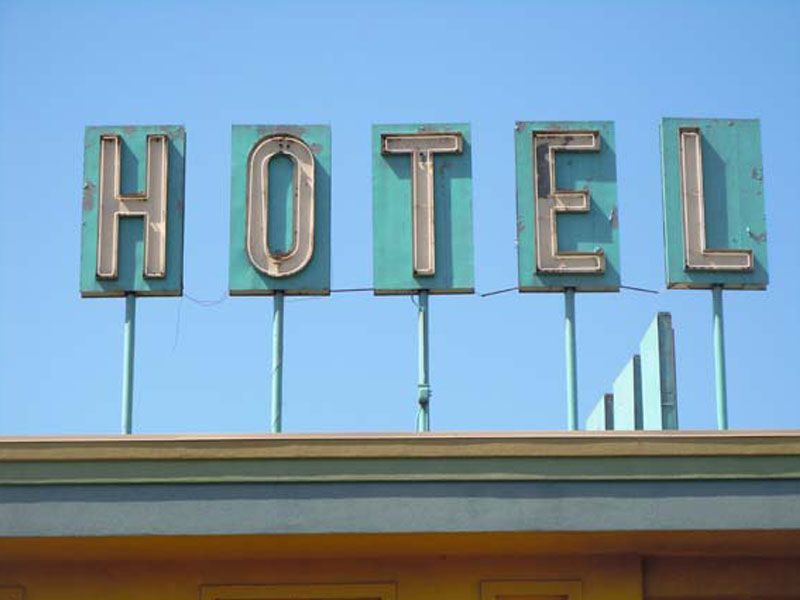 Large turquoise “HOTEL” sign on a rooftop against a clear blue sky, Denver, Colorado