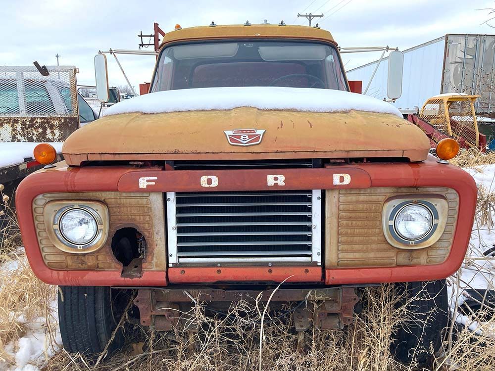 Front view of an old rusted red Ford truck parked outdoors in a snowy lot, York, Nebraska