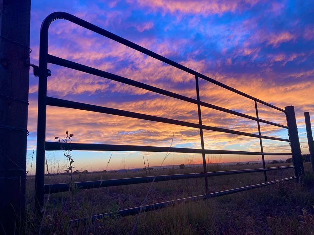 Sunset behind the silhouette of a ranch gate in Peyton, Colorado