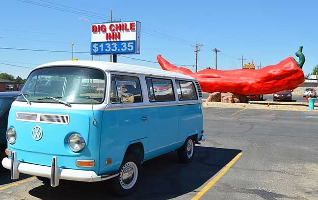 Light blue vintage van parked by a giant red chili pepper statue and “Big Chile Inn” sign, Las Cruces, New Mexico