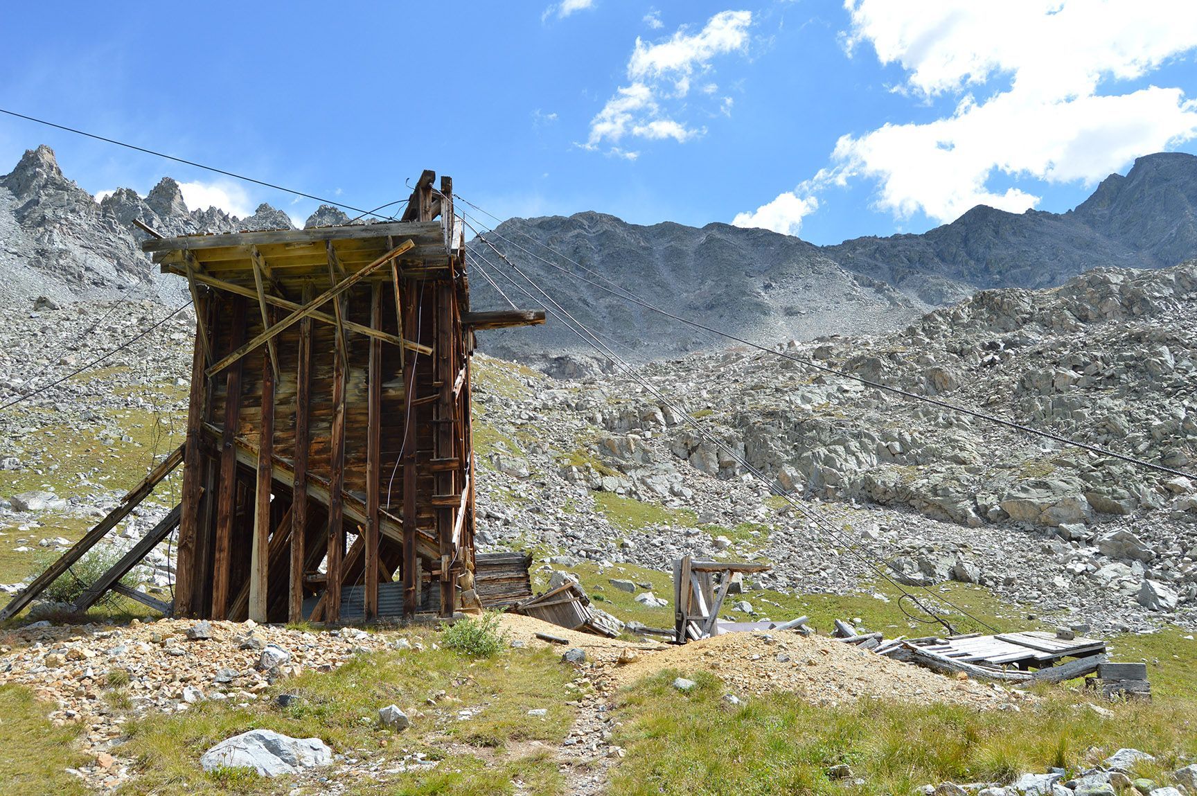Rustic wooden shed in a rocky mountain valley under a bright blue sky with clouds. Mayflower Gulch, Colorado, Gold Crest Mine