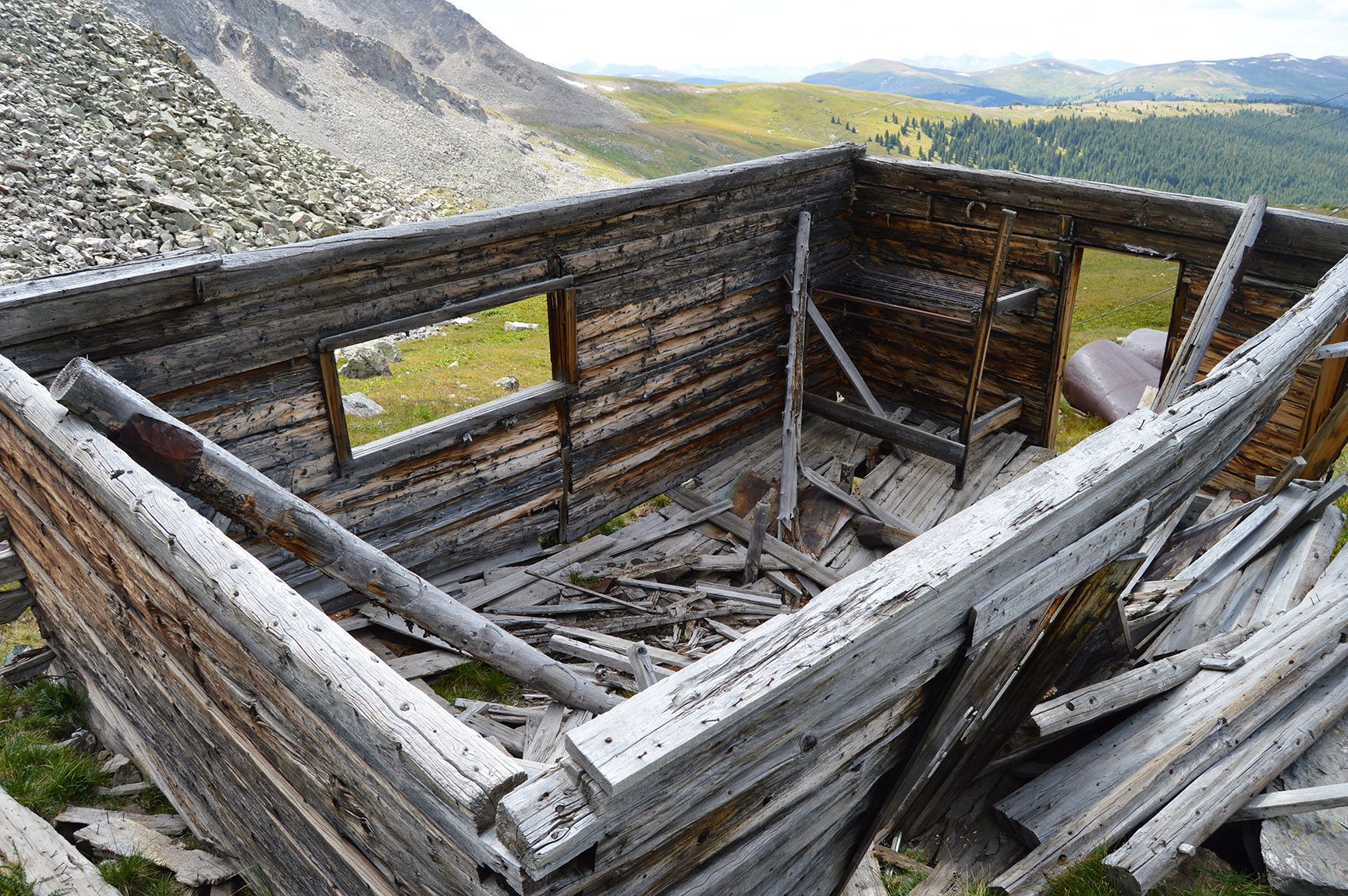 Collapsed wooden cabin in a rocky mountain landscape, with mountains and green valley in the background, Mayflower Gulch, Colorado
