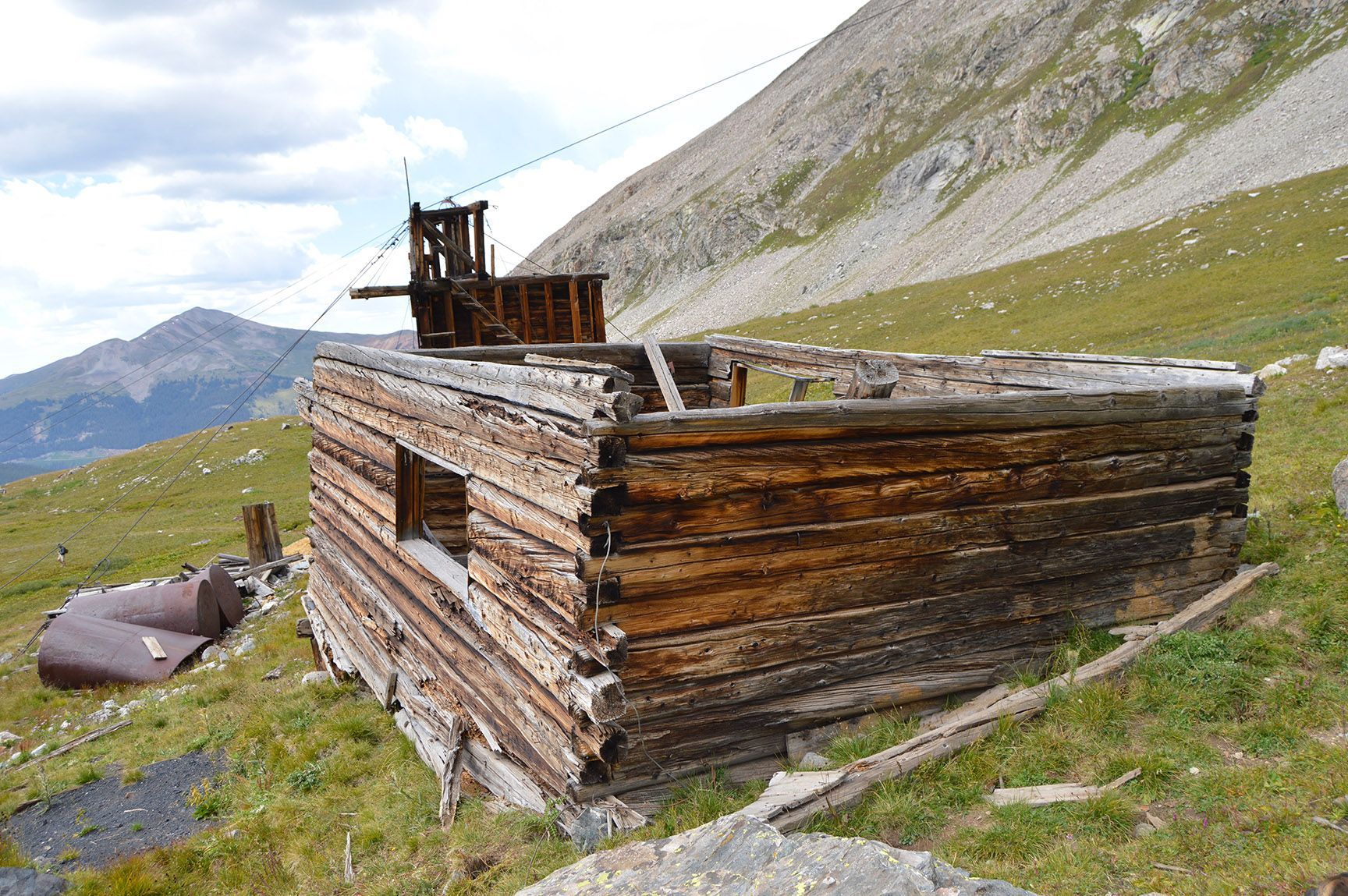Weathered wooden cabin on a grassy mountainside with rocky slopes in the background, Mayflower Gulch, Colorado