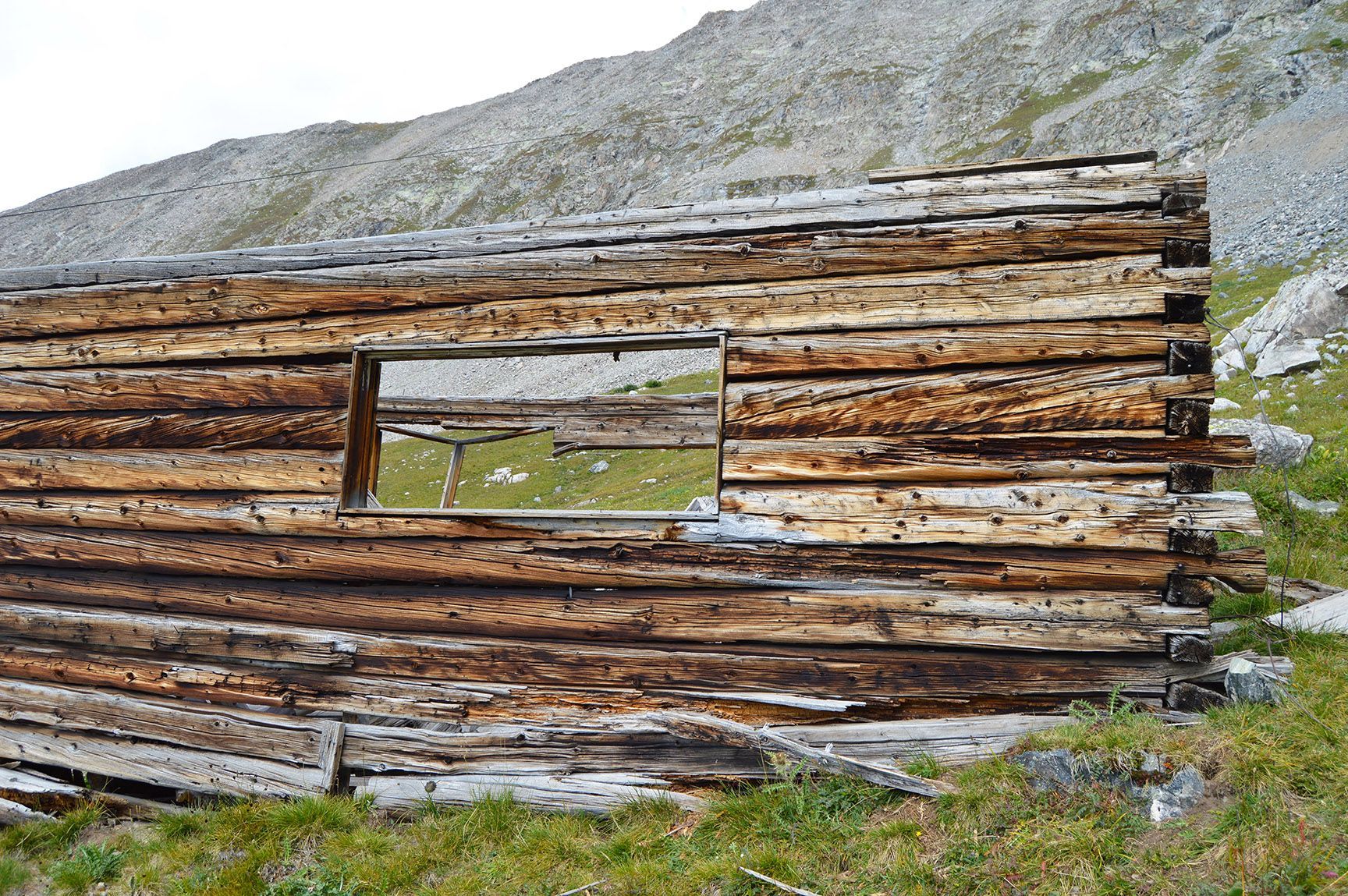 Weathered wooden cabin wall with a window, set in a rocky mountain landscape, Mayflower Gulch, Colorado