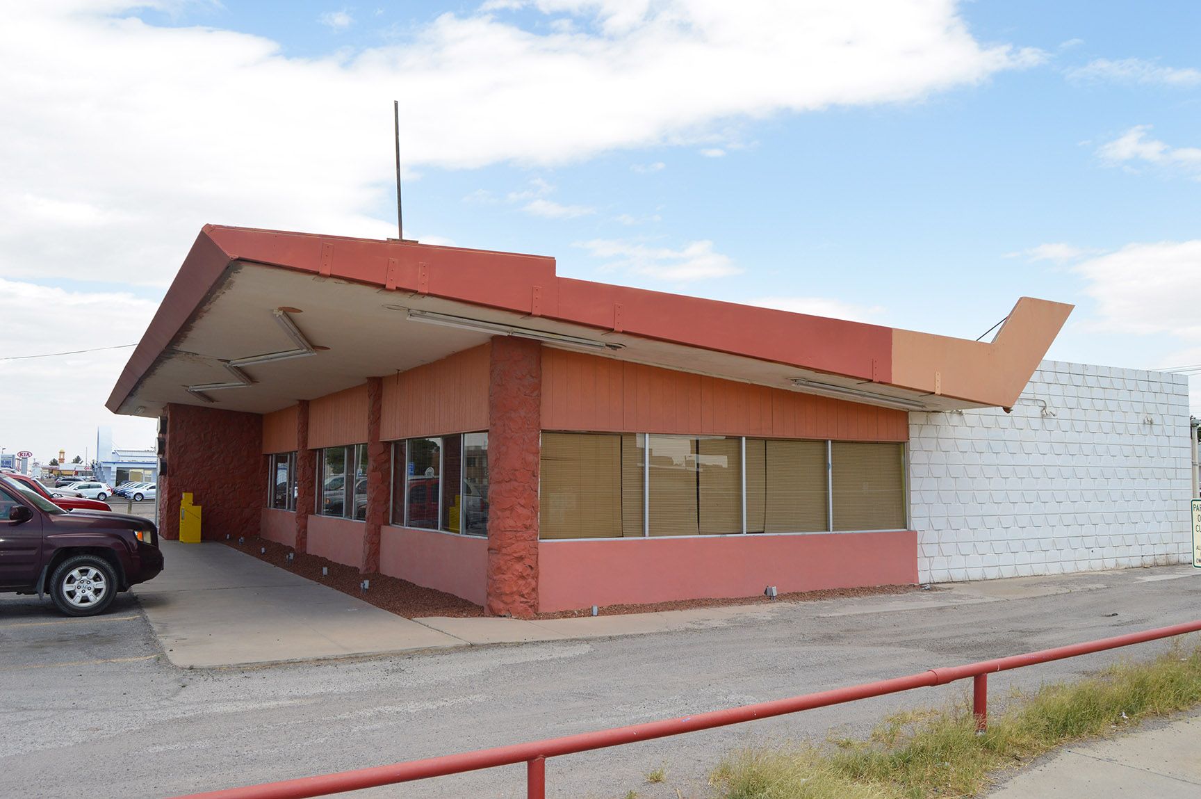 Exterior of a small roadside diner with a red roof and brick facade under a cloudy sky