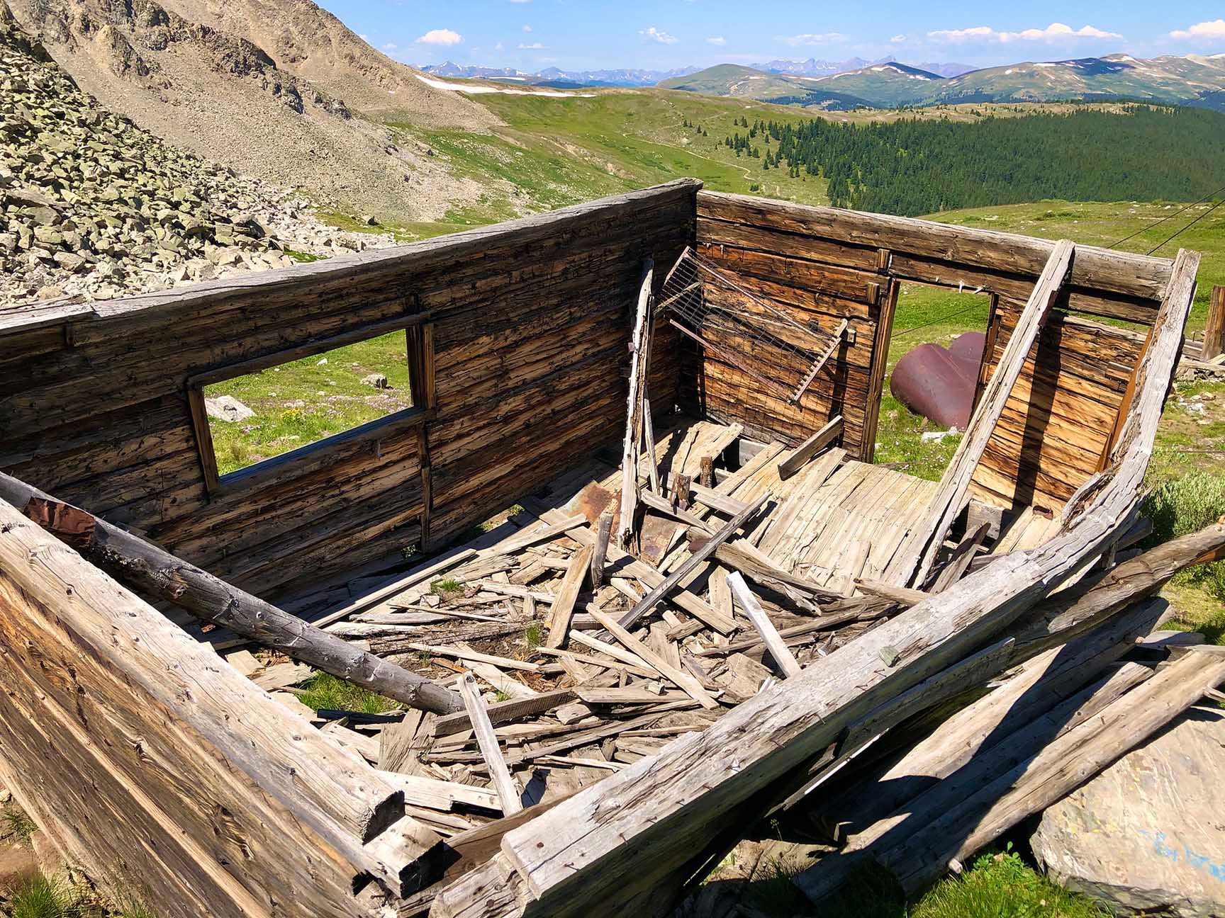 Ruined wooden cabin frame in a rocky mountain landscape with a distant valley view, The ruins of an old cabin, Mayflower Gulch, Colorado