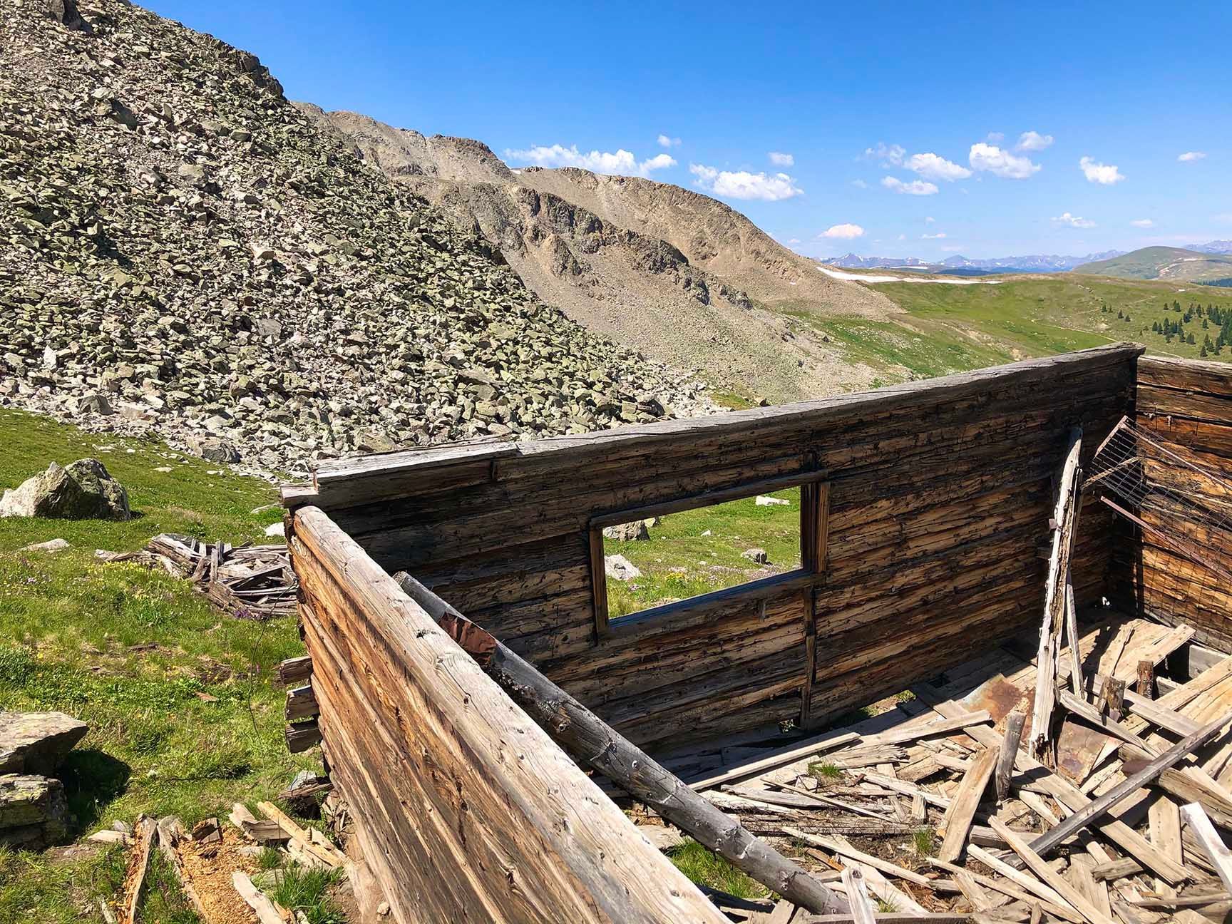 Ruins of a stone and wood building in a rocky mountain valley under a blue sky, The ruins of an old cabin, Mayflower Gulch, Colorado