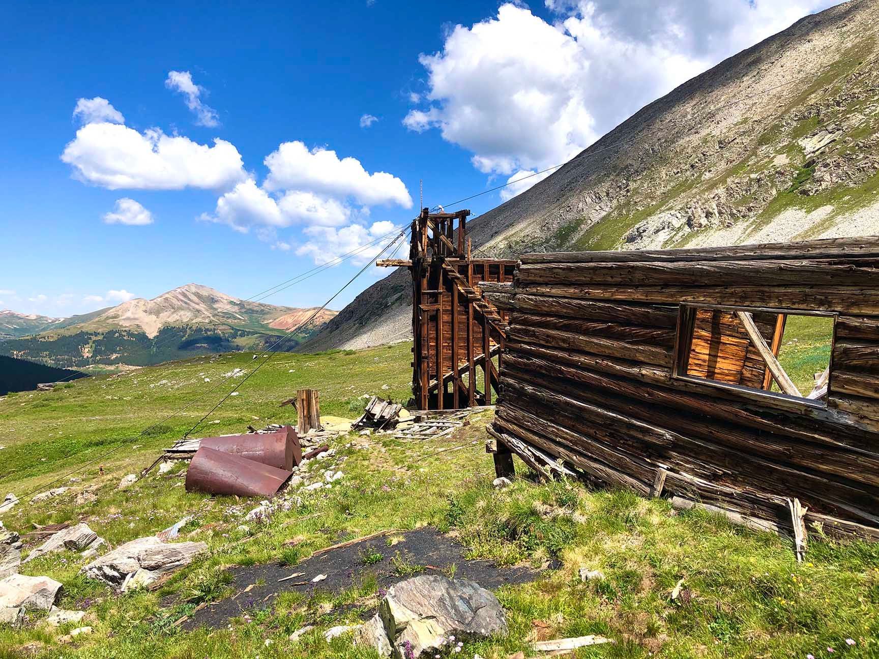 Rustic wooden fence in a mountain meadow under a bright blue sky with clouds, The ruins of an old cabin, Mayflower Gulch, Colorado