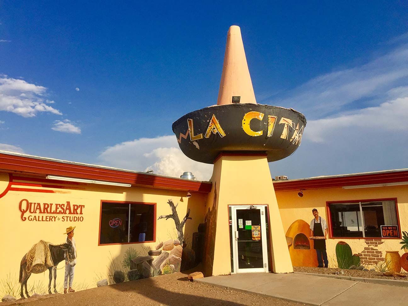 Desert museum entrance with a tall tower sign and painted adobe walls under a blue sky