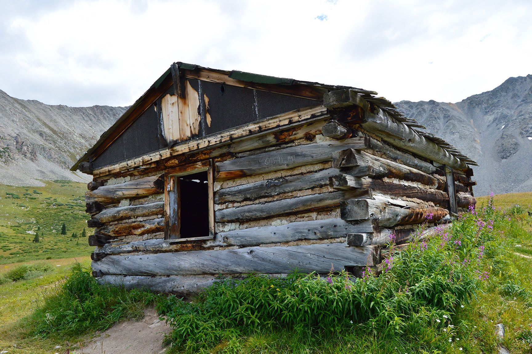 Old weathered wooden cabin in a grassy mountain landscape with rocky peaks behind it, The ruins of an old cabin, Mayflower Gulch, Colorado