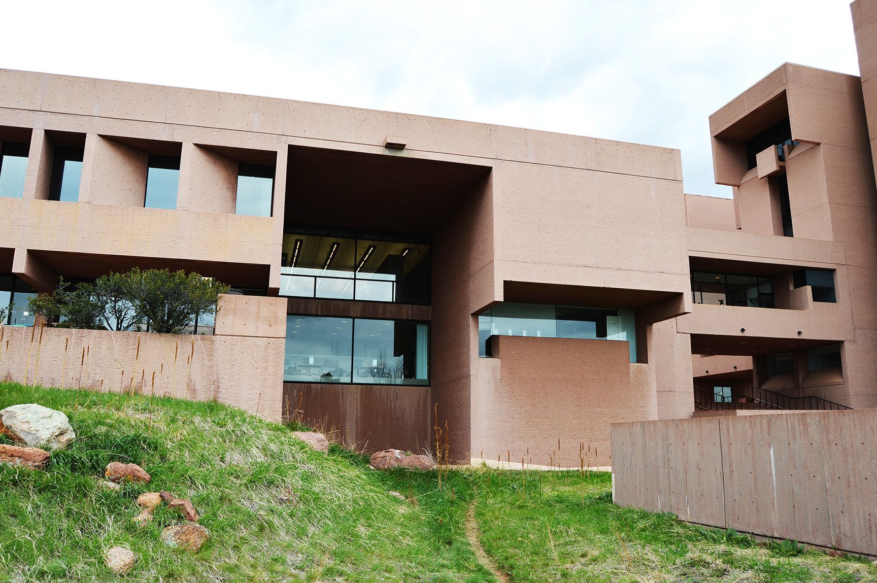 Modern concrete building with large rectangular openings and a grassy slope in front