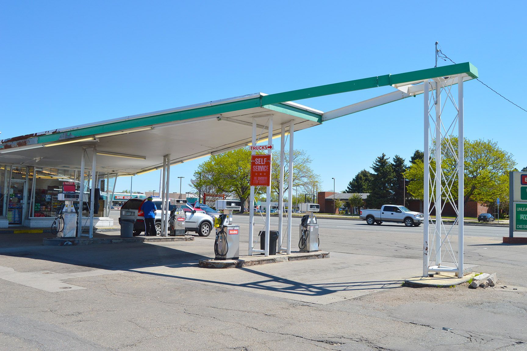 Gas station canopy over pumps and parked cars on a sunny day