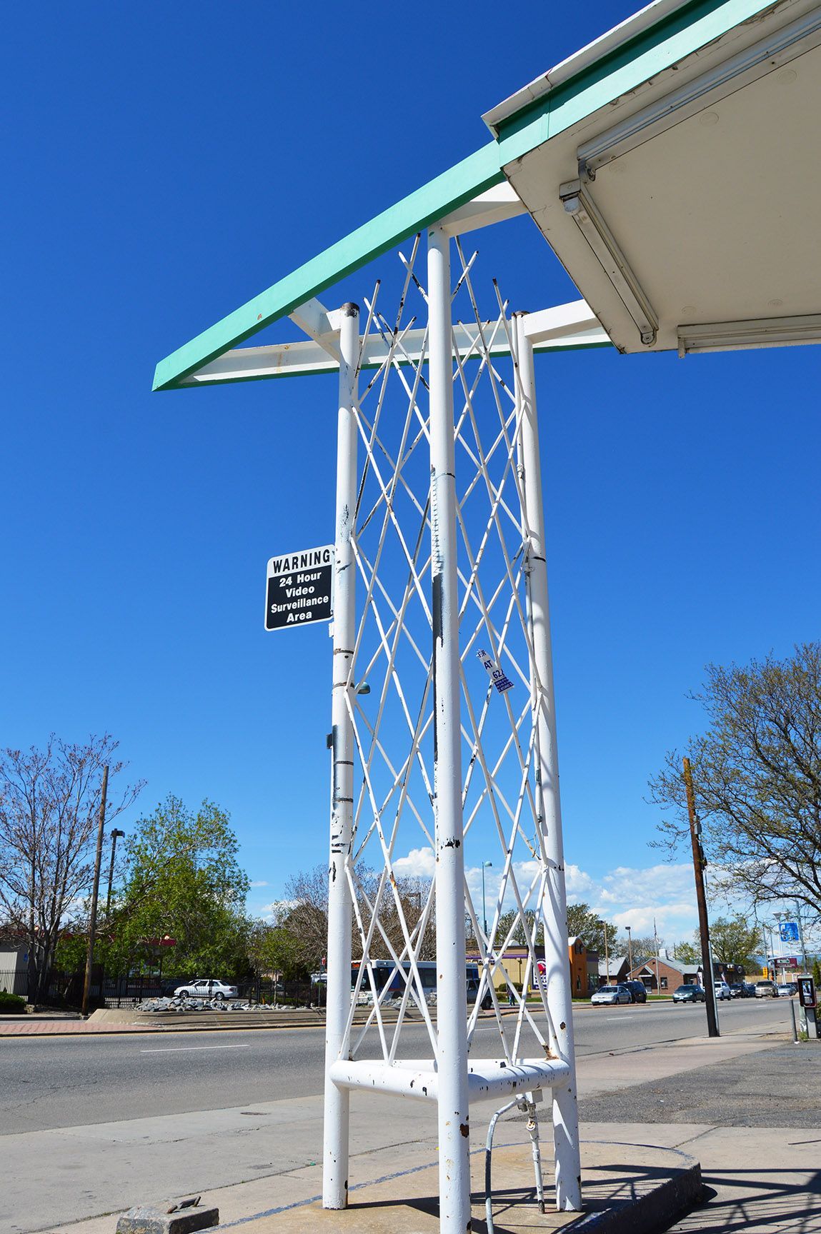 White metal canopy support tower beside a parking lot under a blue sky