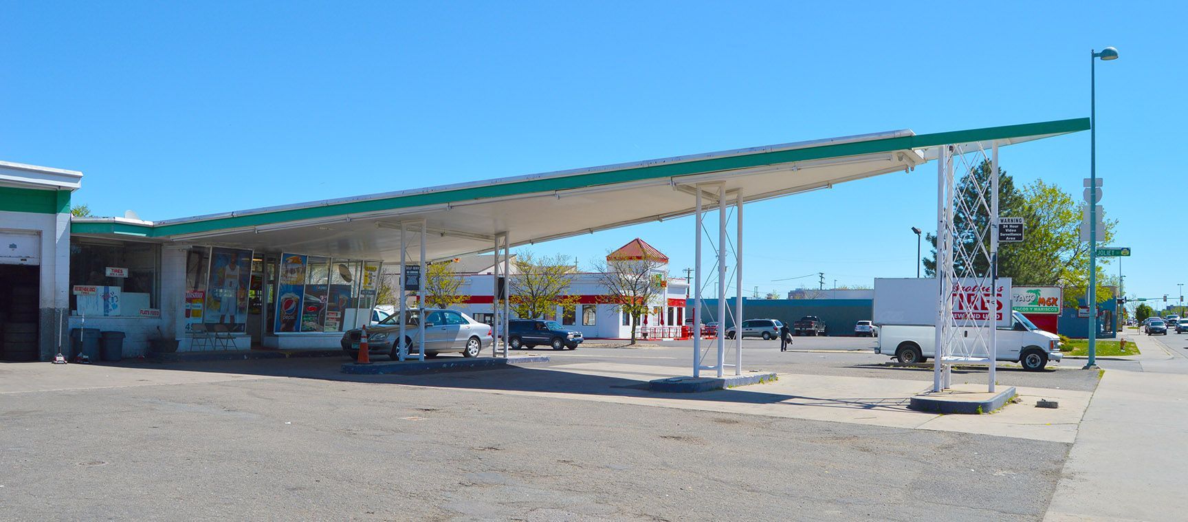 Gas station canopy over parked cars and pumps on a sunny day