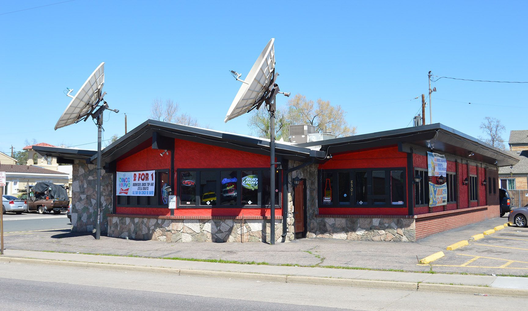 Red and black roadside diner with satellite dishes and a striped awning on a sunny street corner