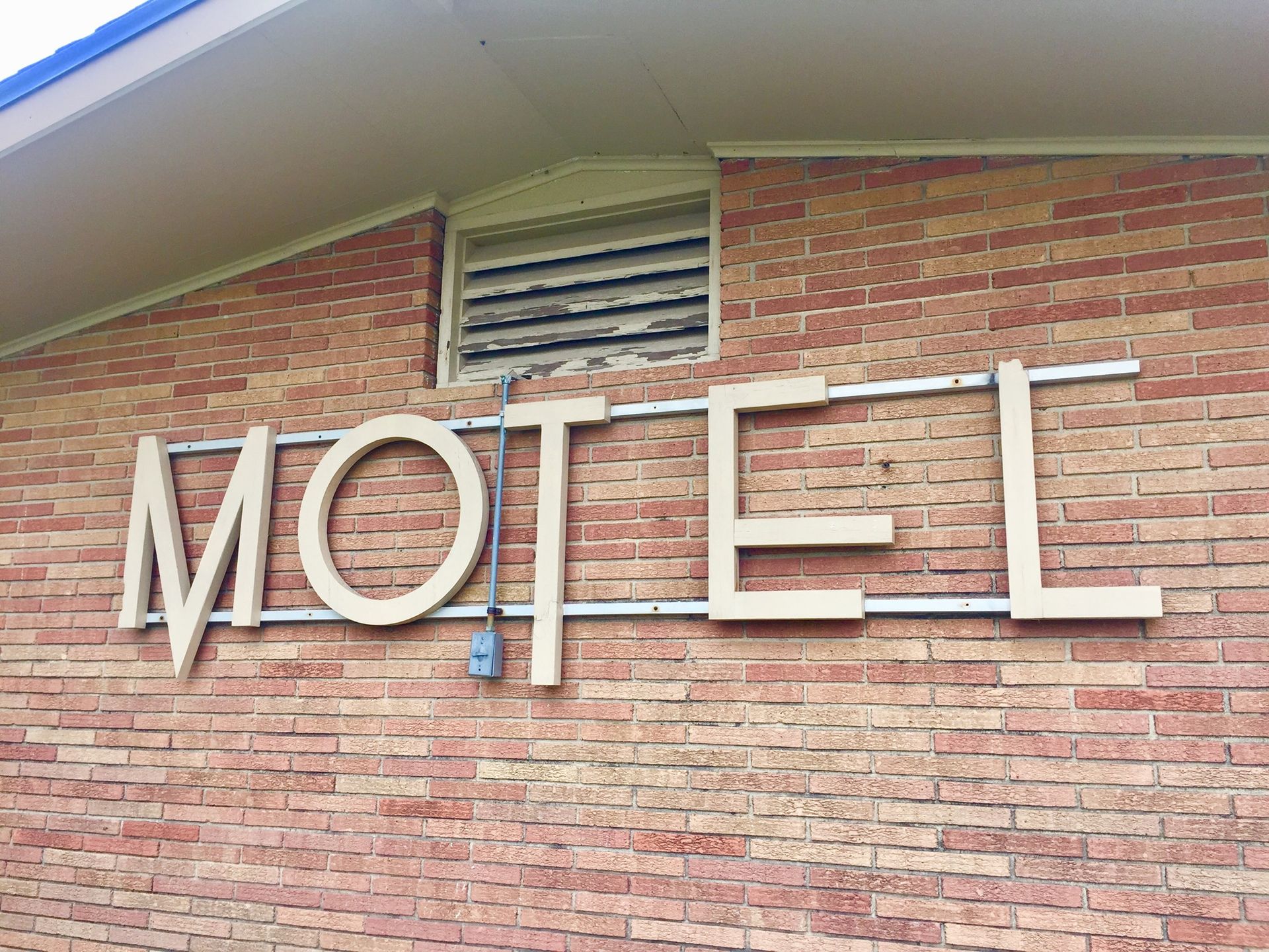White “MOTEL” sign on a brick building facade