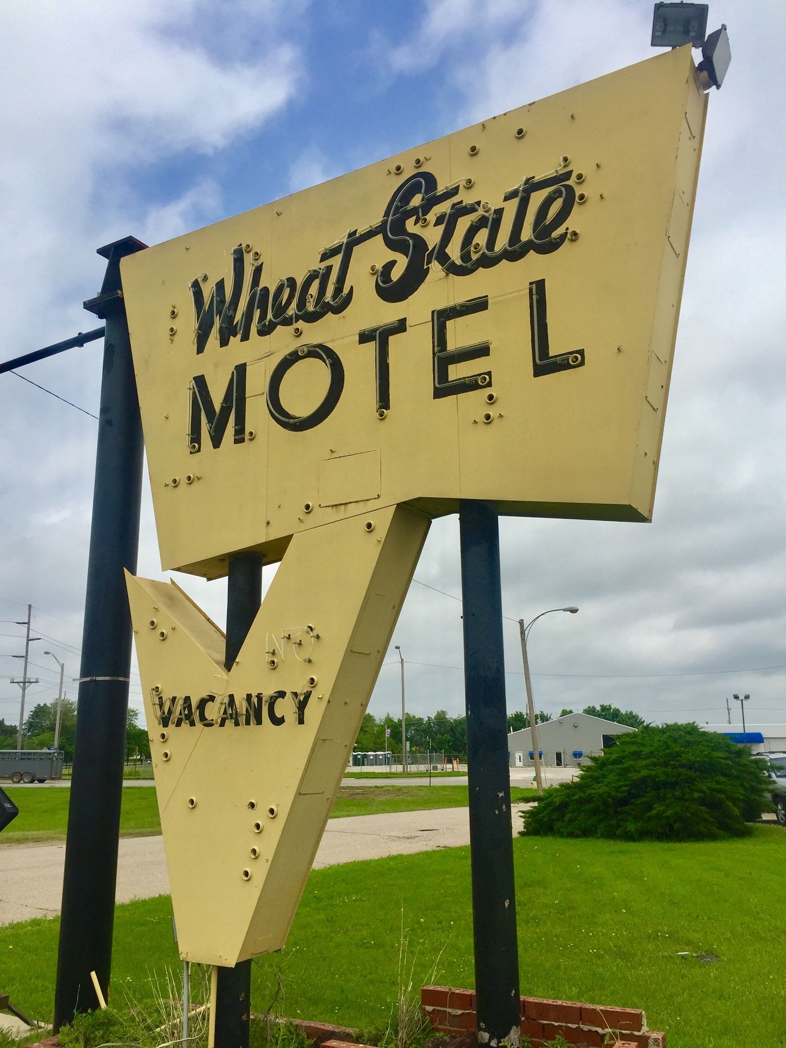 Weathered yellow motel sign reading “Westgate Motel” with “Vacancy” in a roadside lot