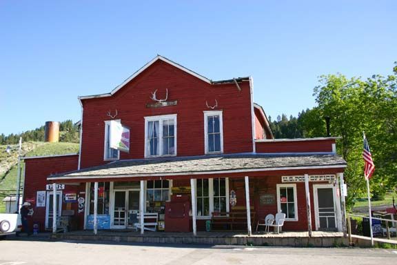 Red historic building with white trim, storefront windows, and an American flag on a sunny day