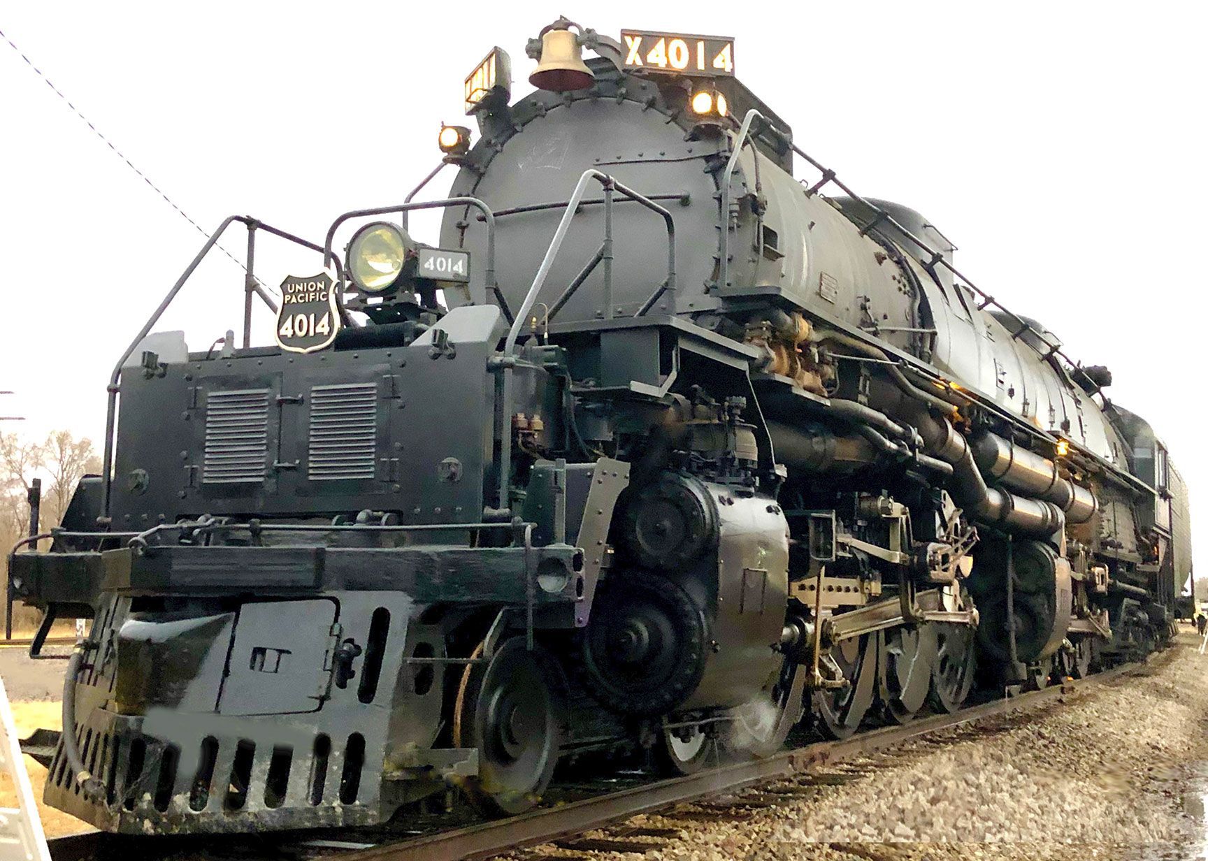 Massive black steam locomotive numbered 4014 on railroad tracks, front view in an industrial setting
