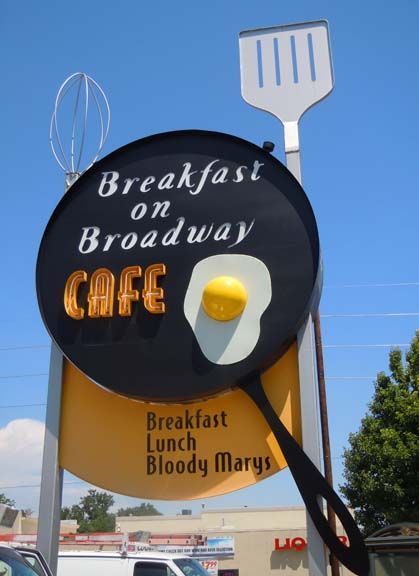 Breakfast on Broadway cafe sign with a fried egg and a large fork against a blue sky