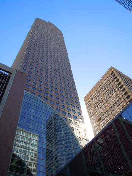 Tall glass skyscrapers viewed from below against a clear blue sky.