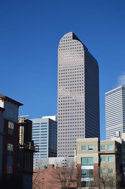 Tall curved skyscraper against a clear blue sky, with shorter buildings in the foreground.