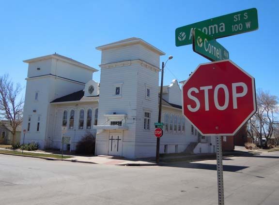 Street corner with a red STOP sign and green street signs in front of a white building.