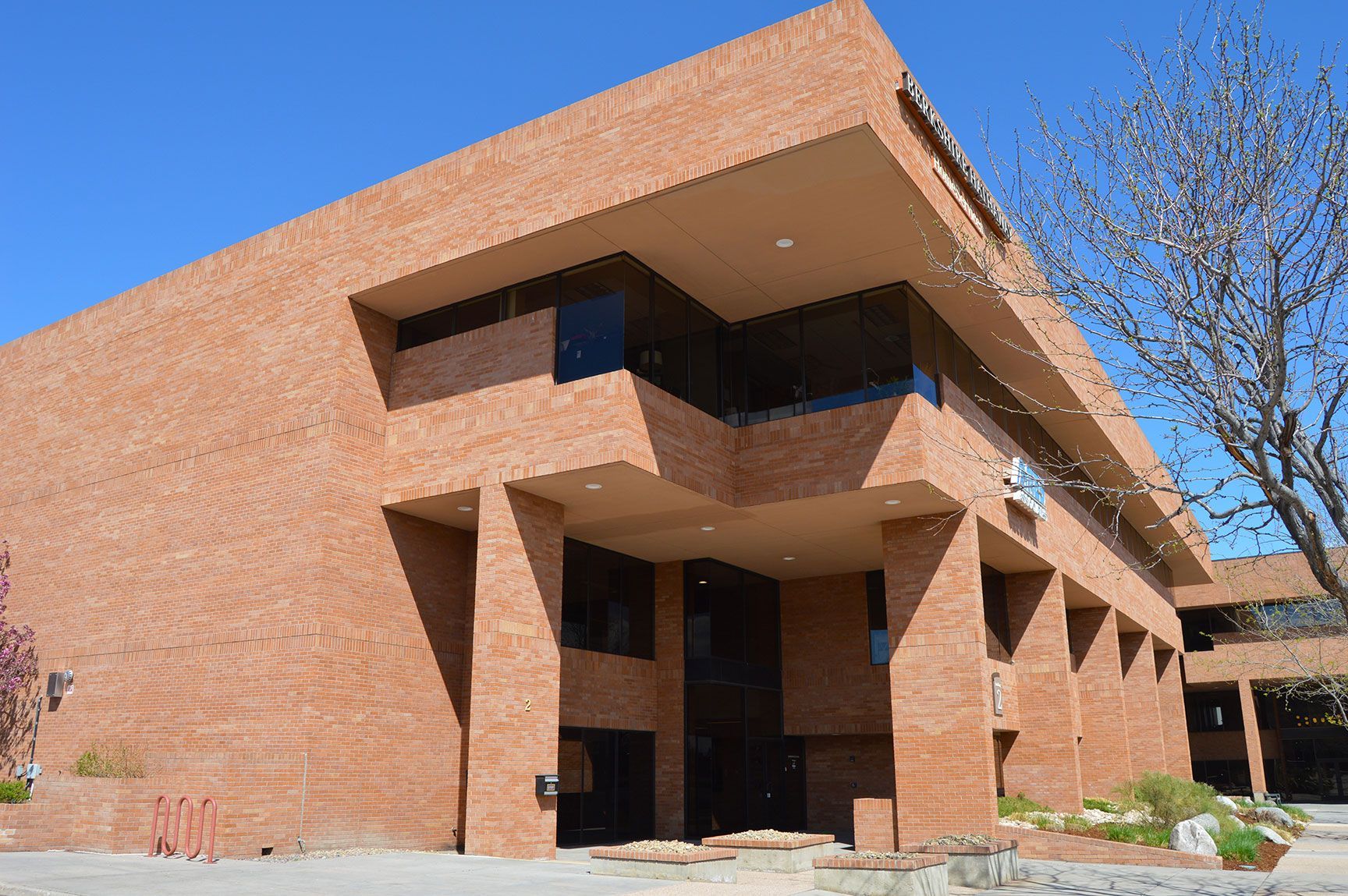 Modern brick building with angular overhangs and windows under a clear blue sky