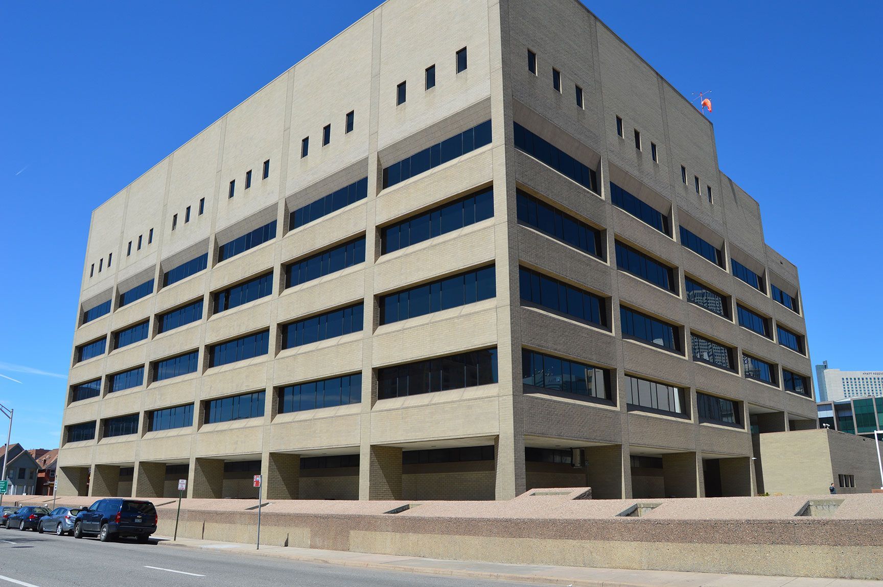 Large beige office building with many windows on a street corner under a clear blue sky
