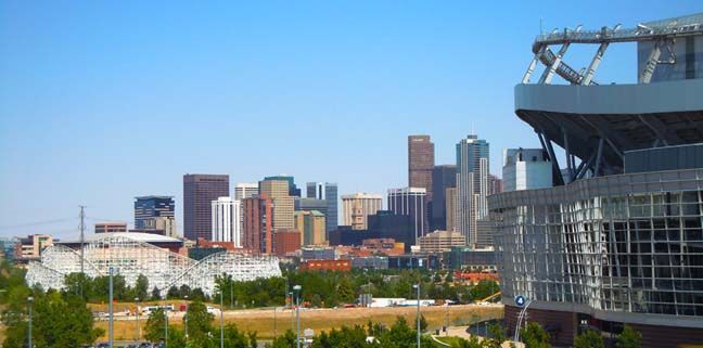 City skyline with modern buildings beside a large stadium under a clear blue sky