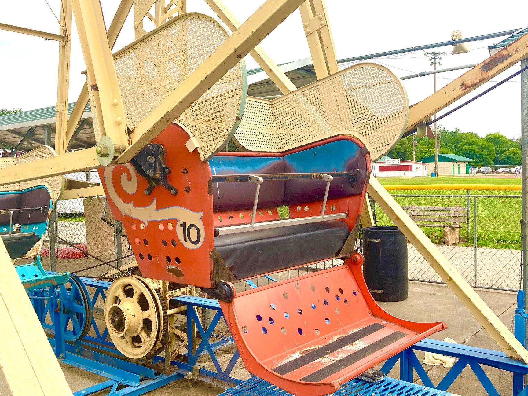Old red Ferris wheel seat with blue frame at an amusement park