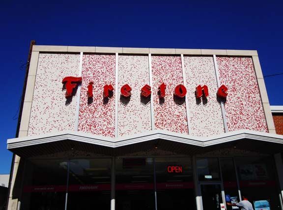 Storefront with red “Tires” sign above an open entrance against a bright blue sky