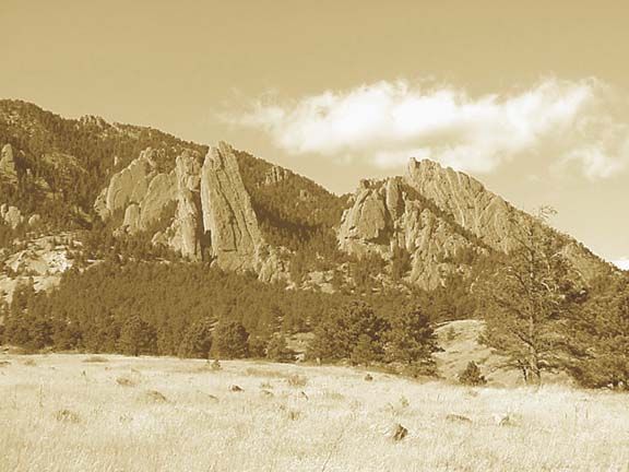 Sepia-toned mountain ridge above a rocky, grassy plain with a bright sky