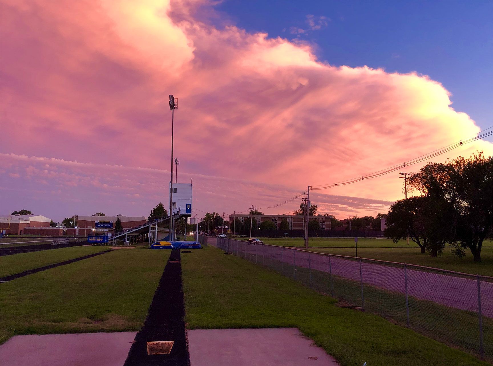 Park at dusk with a pink cloudy sky and a tall flagpole in the center