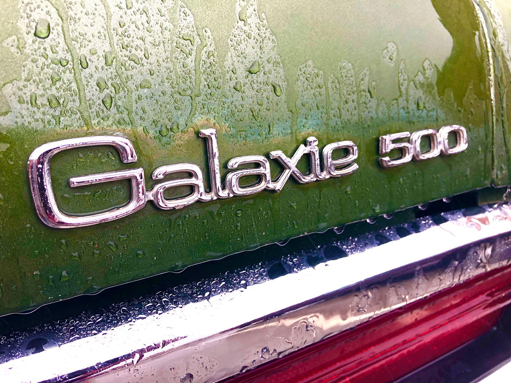 Close-up of a green car badge reading “Galaxie 500” above a red taillight.
