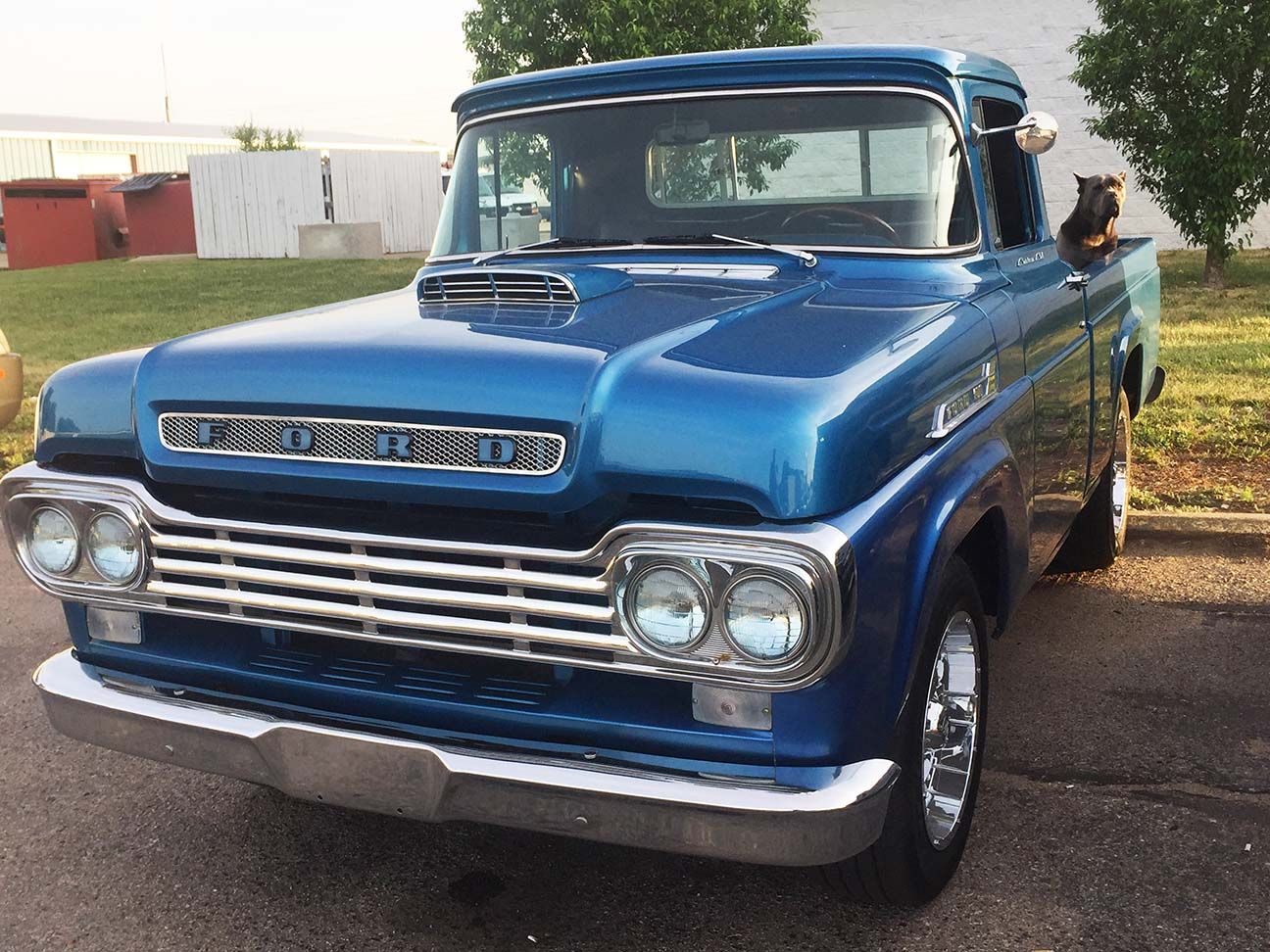 Blue vintage pickup truck parked outdoors on a paved lot, dog sitting in the bed of the truck, Salina, Kansas