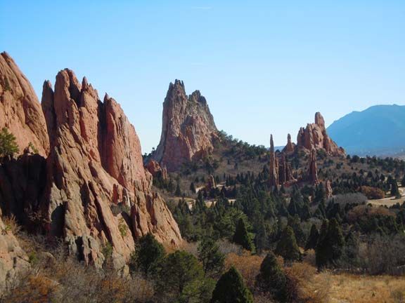 Red sandstone rock spires rising above a forested valley under a clear blue sky