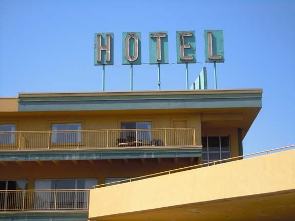 Hotel sign on a tan building against a clear blue sky
