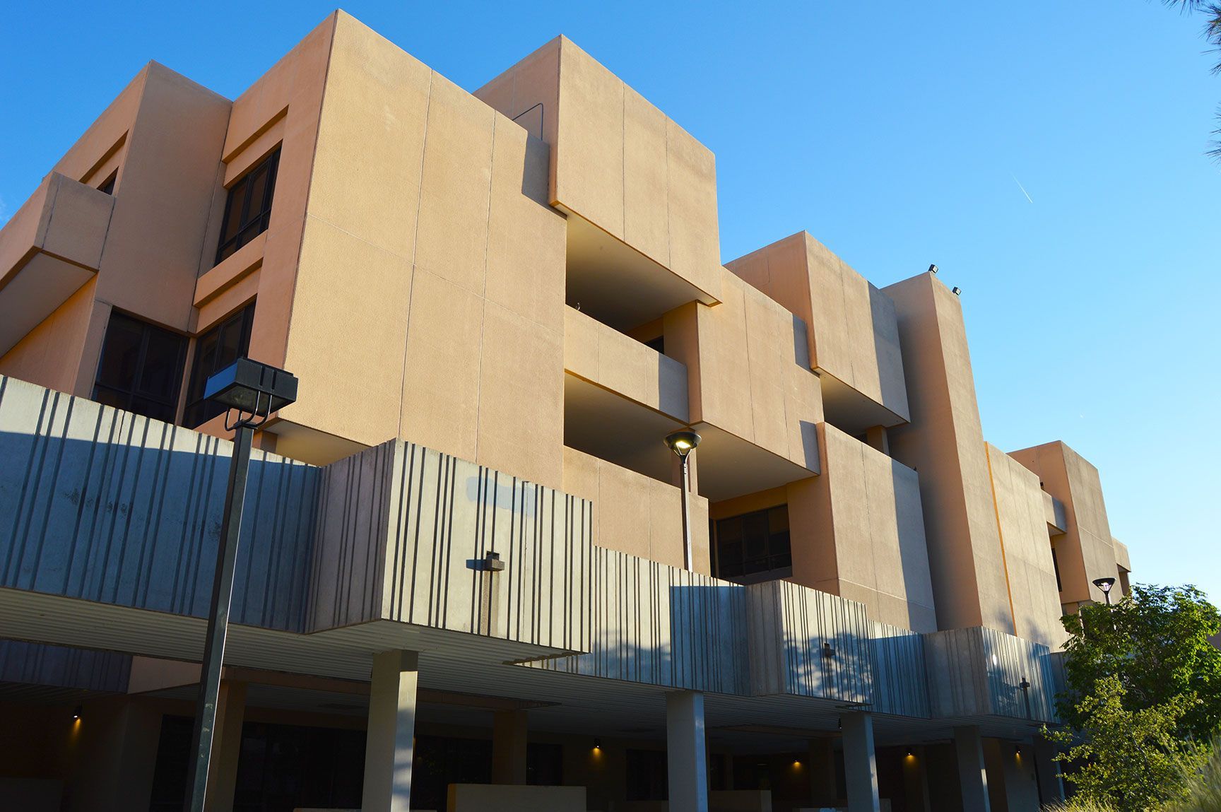 Modern tan apartment building with balconies and blue sky background
