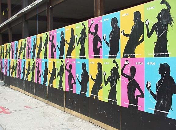 Colorful posters of silhouetted dancers and athletes lined along a sidewalk wall.