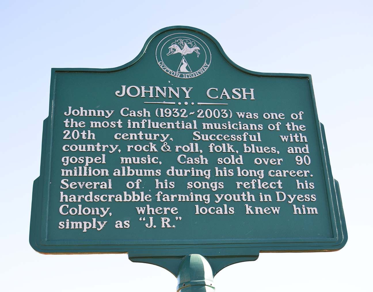 Green historical marker for Johnny Cash in Dyess Colony, with white text and a decorative top emblem