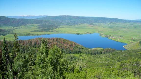Blue lake surrounded by green forested hills under a clear sky