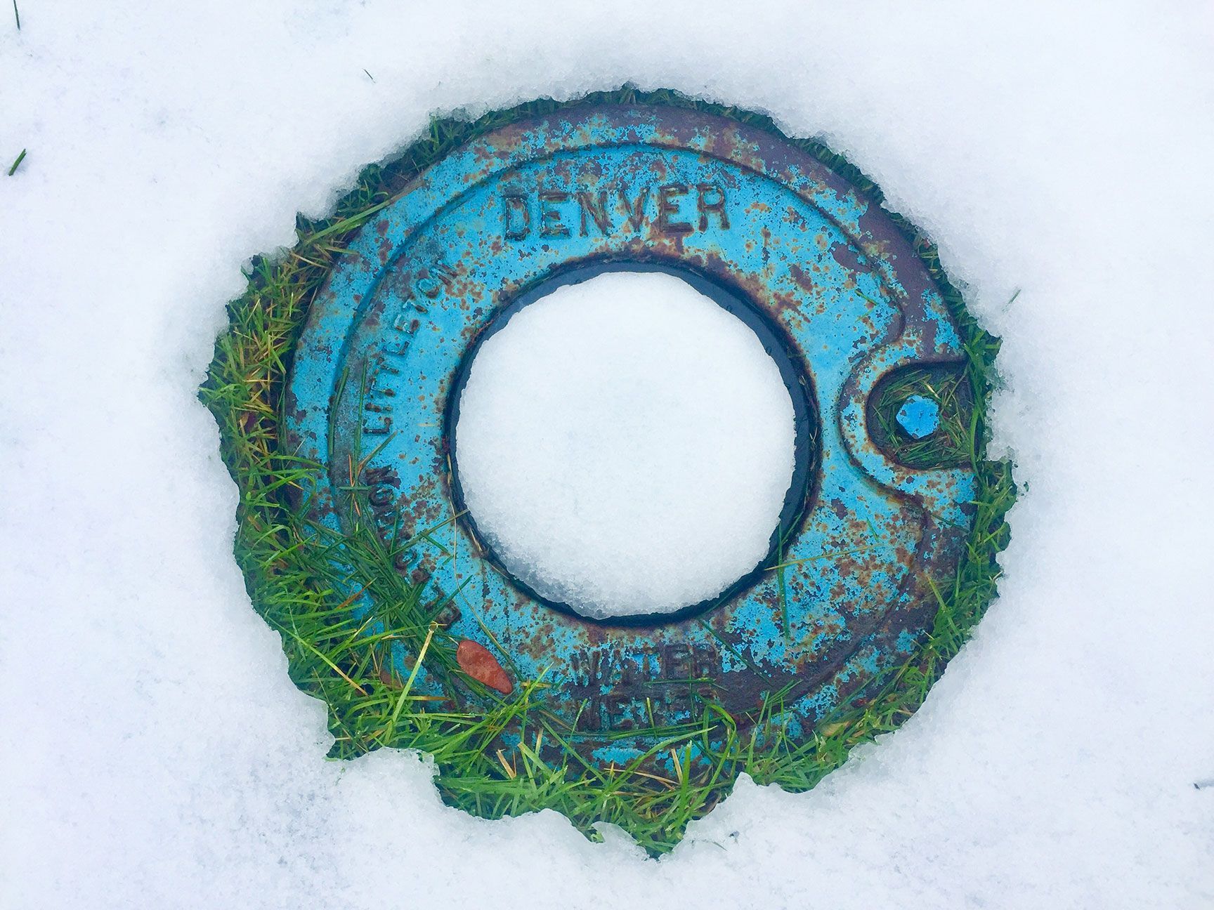 Rusty blue-green metal ring with a central hole lying in snow, Denver, Colorado