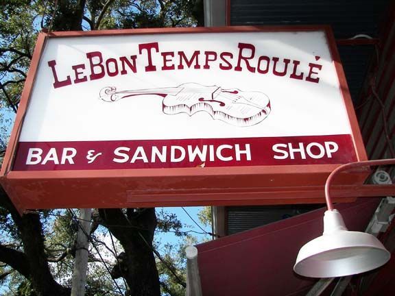 Red sign for Le Bon Temps Roulé bar and sandwich shop with white lettering and a guitar graphic