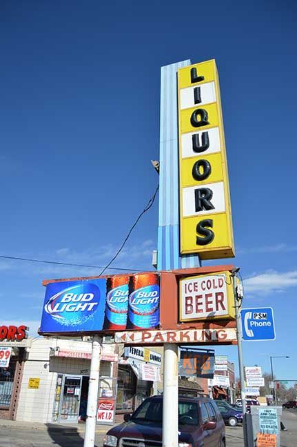 Liquor store with tall vertical “LIQUORS” sign and beer advertisements outside