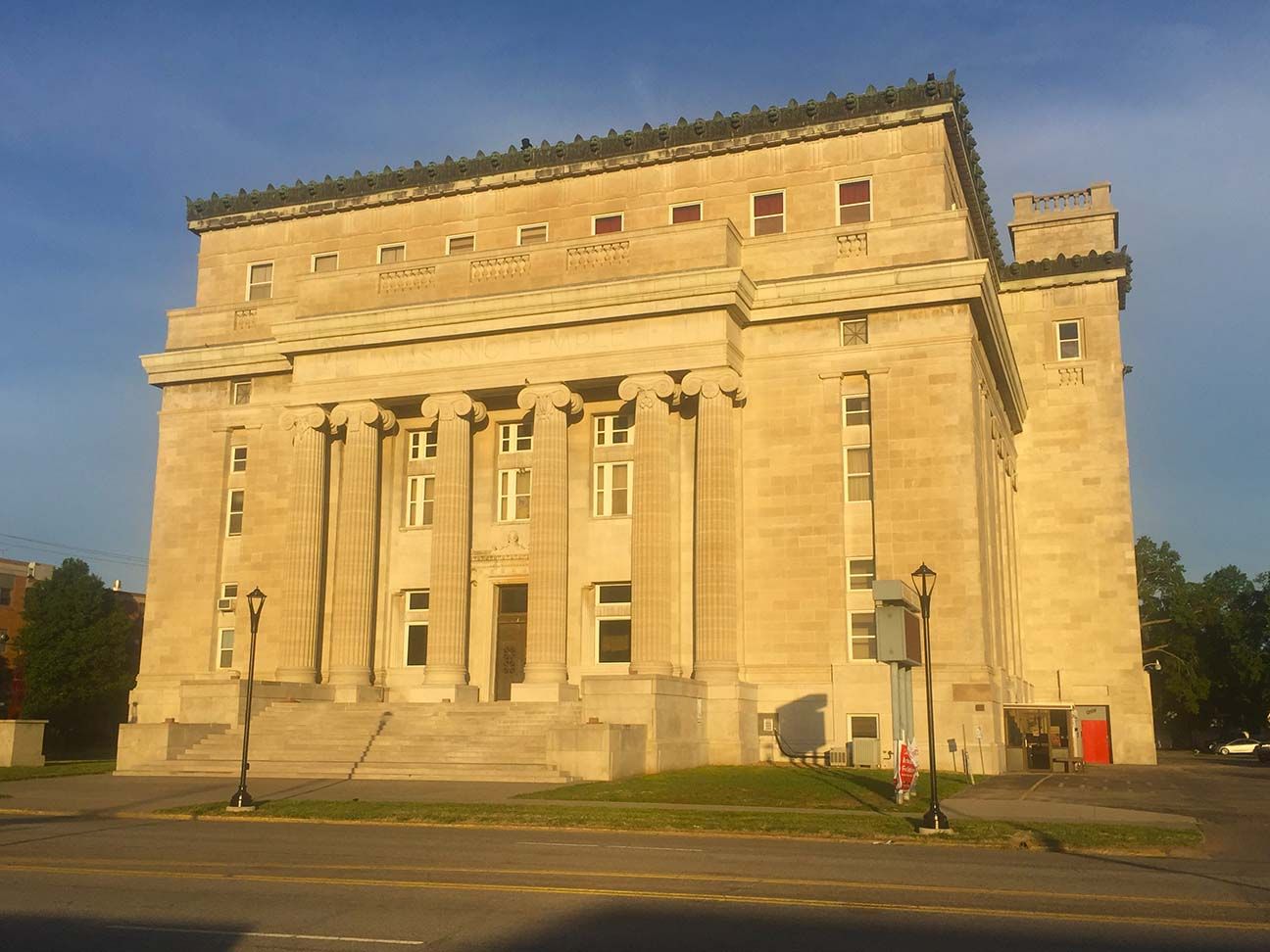 Large stone neoclassical building with tall columns in warm sunlight under a blue sky